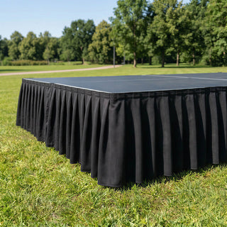 Black stage skirt on outdoor platform in a park setting