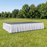 Portable outdoor stage with white skirt in a grassy park setting