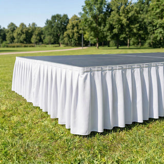 White outdoor event table with pleated table skirt on grass in park