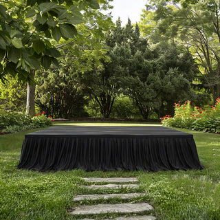 Garden stage setup with black drape in lush green outdoor parkland