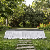 Outdoor garden stage with white draped skirting and lush greenery background
