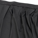 Black pleated skirt fabric close-up with waistband detail