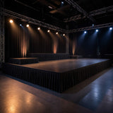 Empty event stage with truss lighting and black draped platforms in a studio