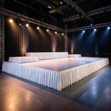 Empty event stage with lighting truss and white draped platform in studio