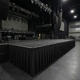 Large empty concert stage with lighting rigs and hanging speakers in a venue