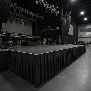 Large empty concert stage with lighting rigs and hanging speakers in a venue