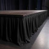 Empty stage with black skirt and wooden platform at an event venue