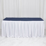White banquet table with navy tablecloth and white skirting on studio backdrop