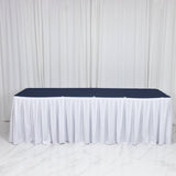 White skirted banquet table with navy tabletop against a white draped backdrop
