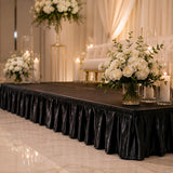 Elegant wedding stage with white floral arrangements, candles, and black draping