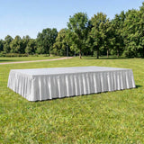 White rectangular event stage with skirting on grass in a park