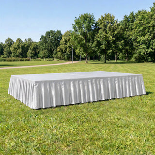 White rectangular event stage with skirting on grass in a park