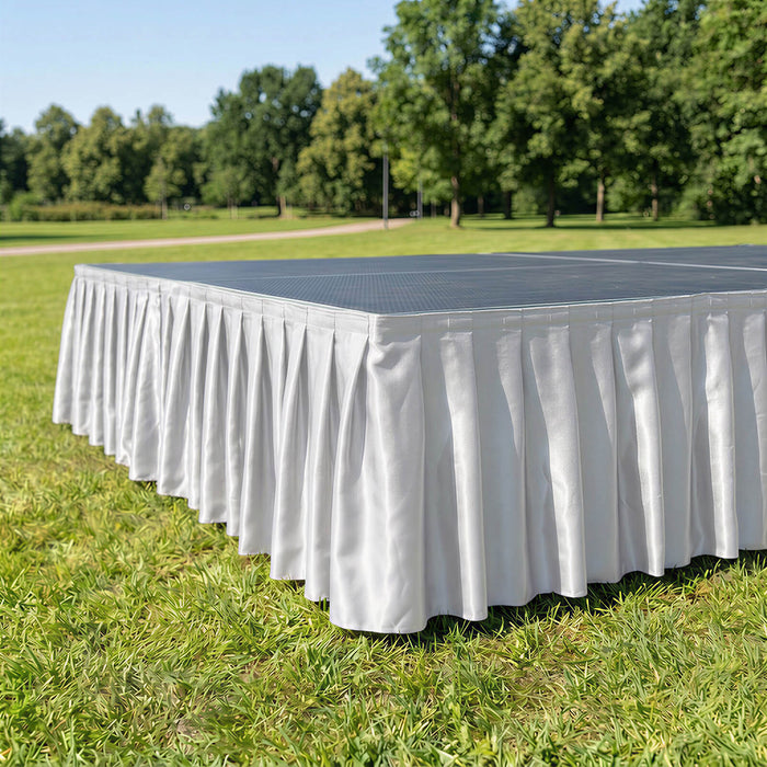 White pleated table skirt on outdoor event table in a park