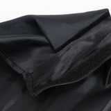 Black satin fabric close-up with folded seams and texture