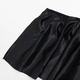 Black satin pleated skirt on white background
