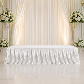 Elegant white wedding stage with floral arrangements and draped backdrop