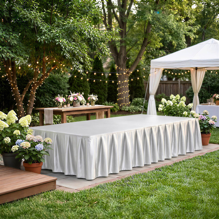 Elegant outdoor event setup with white tablecloths, floral decor, and string lights
