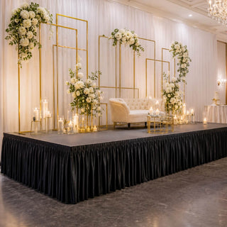 Elegant wedding stage decor with white flowers, gold frames, candles, and sofa