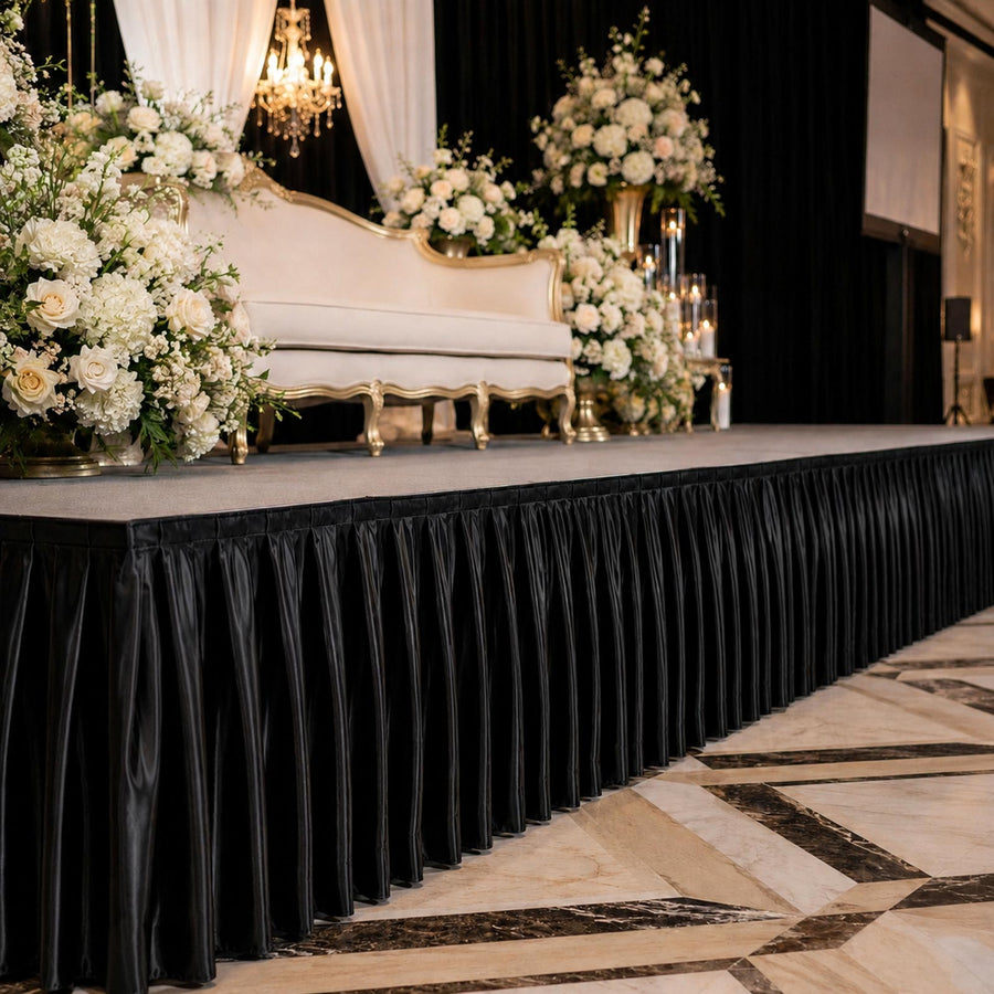 Elegant wedding stage with floral arrangements and white sofa on black draped platform