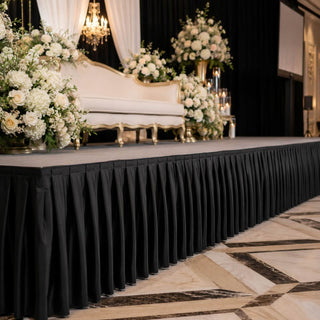 Elegant wedding stage with floral arrangements and white loveseat on black drape backdrop