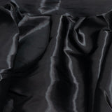 Black satin fabric with glossy folds and soft draped texture