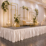 Elegant wedding stage with floral arches, candles, and cream tufted loveseat