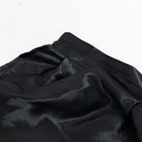 Black satin fabric close-up with stitched seam on white background