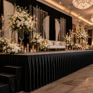 Elegant black and gold wedding stage with white floral arrangements and chandeliers