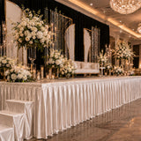 Elegant wedding stage decor with white floral arrangements and candlelit backdrop