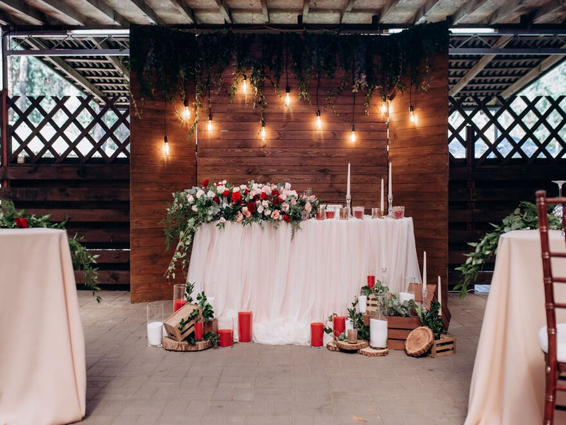 Blush wedding tables under white draping and wood backdrop