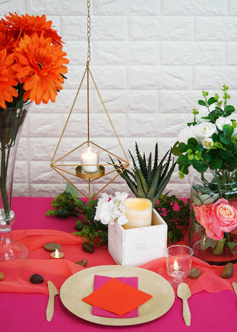 Geometric hanging candle holder beside orange flowers