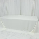 White table draped with fabric on a plain backdrop.
