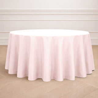 Pink round tablecloth on a wooden floor with elegant draping.