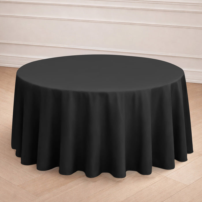 Black round tablecloth on a wooden floor backdrop.