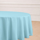 Round light blue tablecloth on a wooden floor.