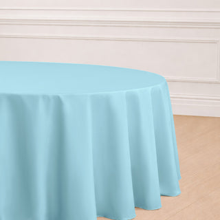 Round light blue tablecloth on a wooden floor.