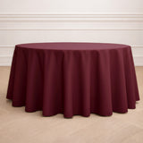 Burgundy round tablecloth on a wooden floor.