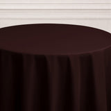 Brown tablecloth on a round table against a neutral backdrop.