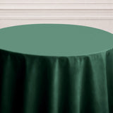 Green tablecloth on a round table against a plain backdrop.