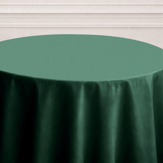 Green tablecloth on a round table against a plain backdrop.
