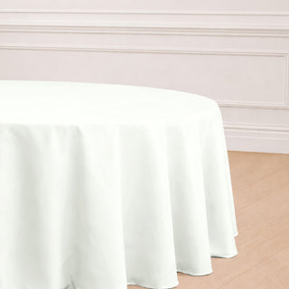 Round white tablecloth on a wooden floor in a stylish setting.