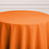 Orange tablecloth on a round table with a neutral background.
