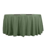 Green round tablecloth with plates on a plain backdrop