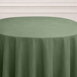 Green tablecloth draped over a round table in a minimalist setting.