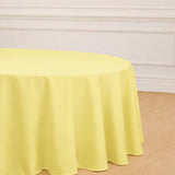 Yellow round tablecloth on a wooden table in a bright room.
