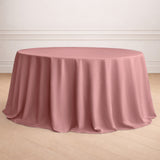 Round pink tablecloth draped over a circular table in a staged setting.