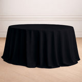 Black round tablecloth on a wooden floor in a styled room setting.