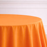 Orange tablecloth draped over a round table against a light background.