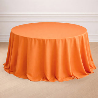 Round orange tablecloth draped elegantly over a circular table.
