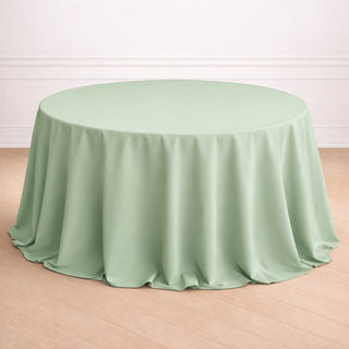 Round mint green tablecloth on a wooden floor.